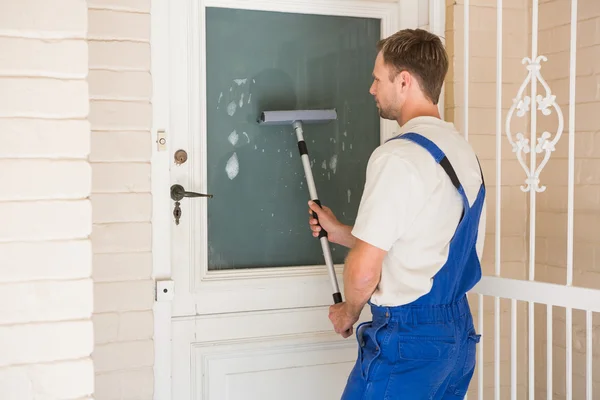 Handyman limpando a janela com rodos — Fotografia de Stock