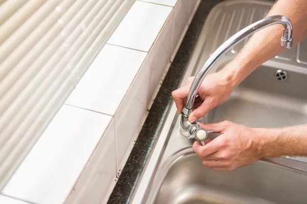 Mann fixiert Wasserhahn mit Zange — Stockfoto