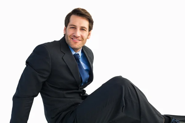 Businessman in suit sitting on floor while looking at camera — Stock Photo, Image