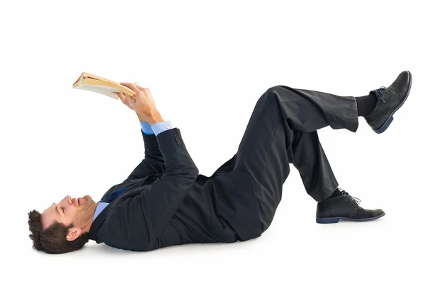 Empresário deitado no chão enquanto lia um livro — Fotografia de Stock