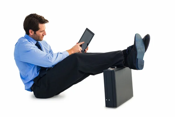 Businessman sitting on the floor with feet up on suitcase — Stock Photo, Image