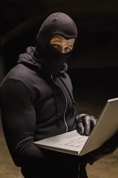 Burglar standing holding laptop while looking at camera — Stock Photo, Image