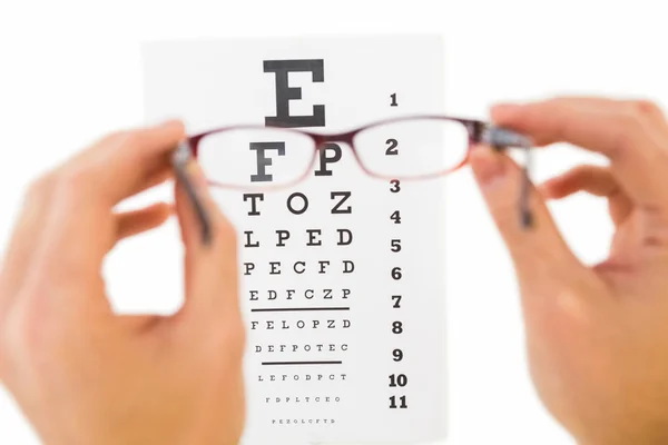 Glasses held up to read eye test — Stock Photo, Image