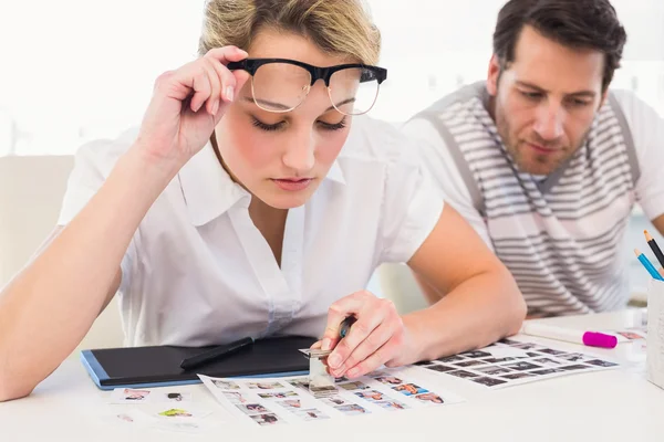 Editor using magnifying loupe to view the contact sheet — Stock Photo, Image