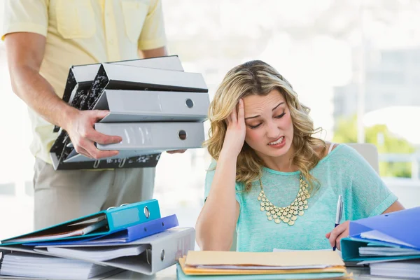 Stressed creative businesswoman with stack of files — Stock Photo, Image