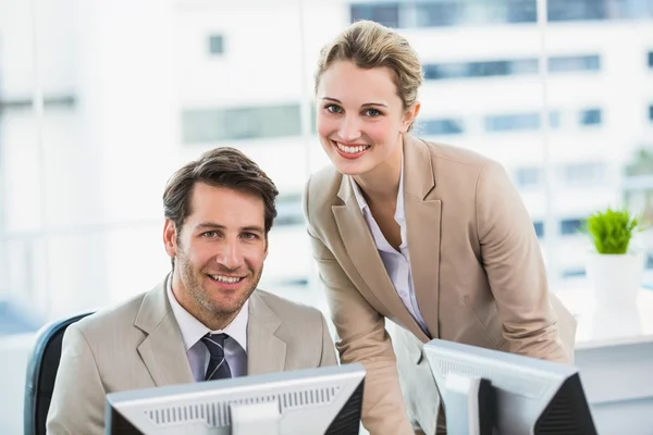 Smiling businessman helping his colleague at a computer — Stock Photo, Image