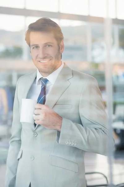 Affärsman holding kopp kaffe genom fönstret — Stockfoto