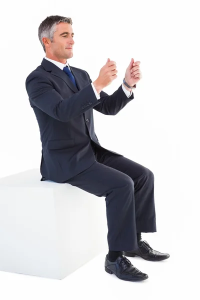 Businessman sitting on a cube with arms out — Stock Photo, Image