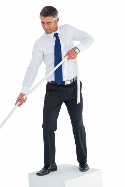 Businessman standing on cube pulling rope — Stock Photo, Image