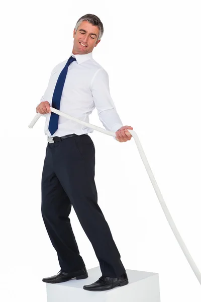 Smiling businessman standing on a cube and pulling rope — Stock Photo, Image