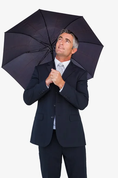 Hombre de negocios sonriente refugiándose con paraguas —  Fotos de Stock