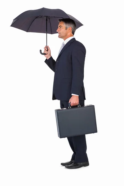 Businessman holding briefcase under umbrella — Stock Photo, Image