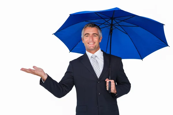 Happy businessman under umbrella with hand out — Stock Photo, Image