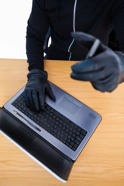 Sección media de un ladrón usando un portátil y un teléfono inteligente — Foto de Stock