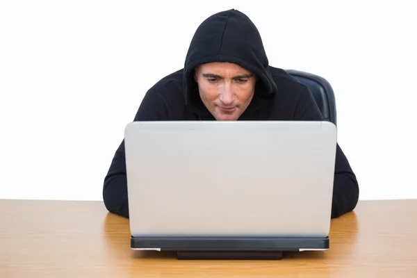 Inbreker die hij in kap jas met behulp van laptop — Stockfoto