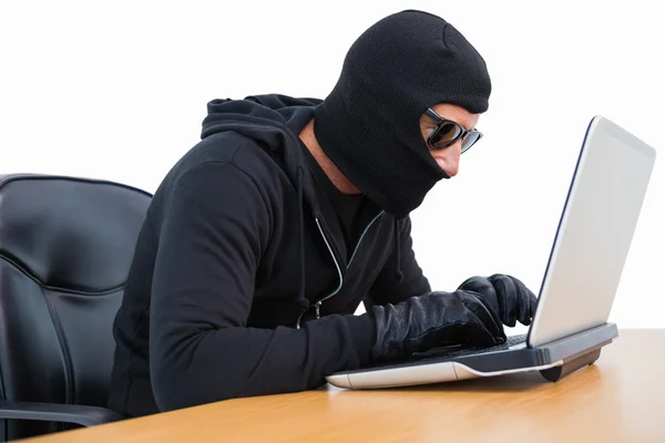 Inbreker die hij in zonnebril met behulp van laptop — Stockfoto