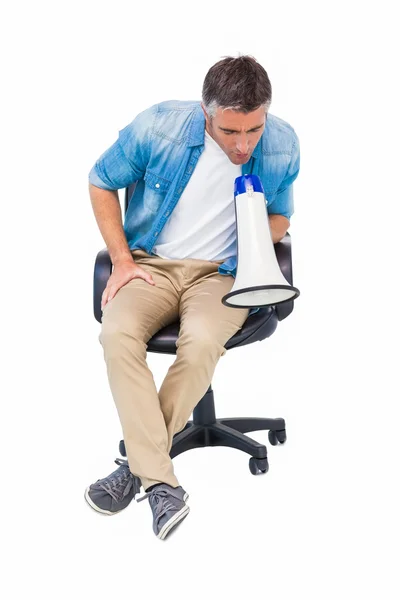 Man zit op een stoel van het Bureau spreken over megafoon — Stockfoto