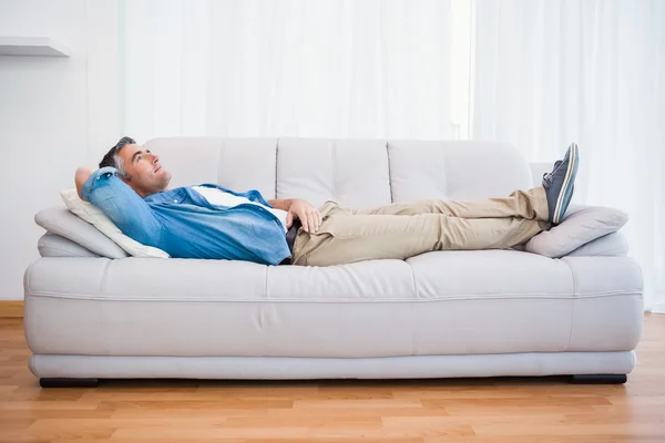 Lächelnder Mann liegt und entspannt auf der Couch — Stockfoto