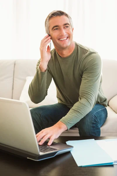 Homme heureux au téléphone en utilisant un ordinateur portable — Photo