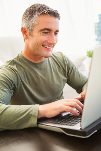 Homme souriant avec les cheveux gris à l'aide d'un ordinateur portable — Photo