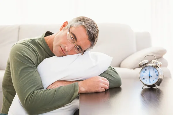 Mann ruht auf Kissen mit Wecker auf dem Tisch — Stockfoto