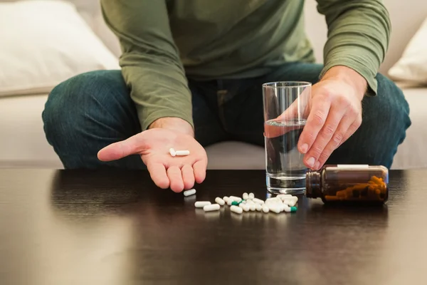 Casual man showing pills on open hand — Stock Photo, Image