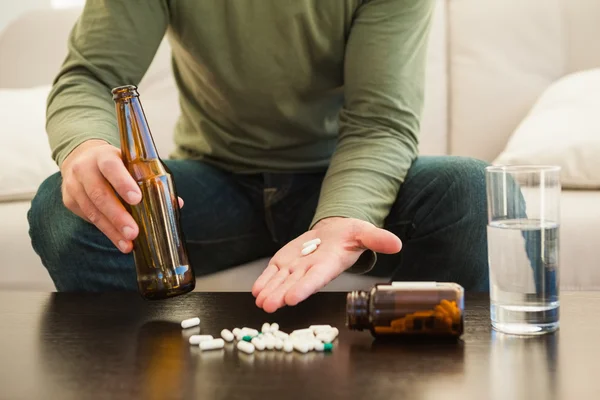 Hombre mostrando pastillas y sosteniendo la botella de cerveza — Foto de Stock