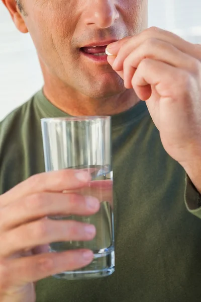 Närbild mitten delen av en man med glas vatten och p-piller — Stockfoto