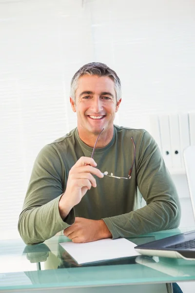 Sorrindo homem casual segurando seus óculos — Fotografia de Stock