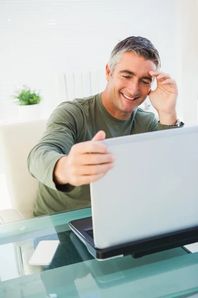 Веселый человек сидит и держит свой ноутбук — стоковое фото