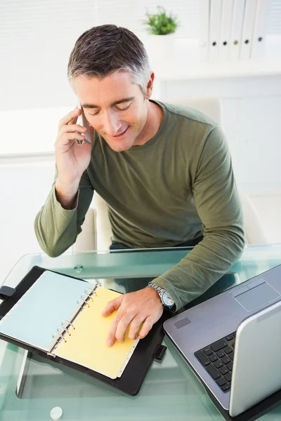 Homem ao telefone a verificar as anotações — Fotografia de Stock