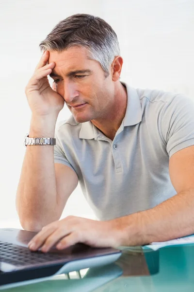 Cansado homem sentado e usando seu laptop — Fotografia de Stock