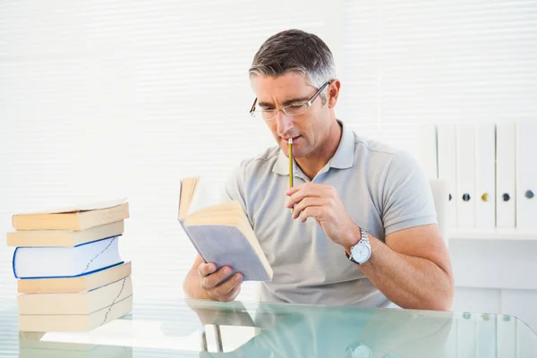 Hombre con gafas pensando y leyendo un libro — Foto de Stock