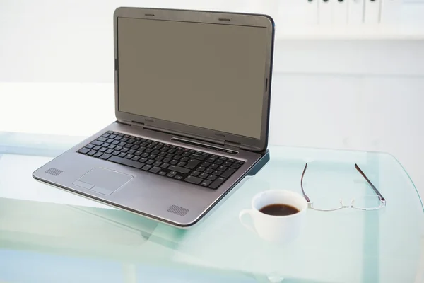 Laptop på skrivbordet med mugg kaffe och glasögon — Stockfoto