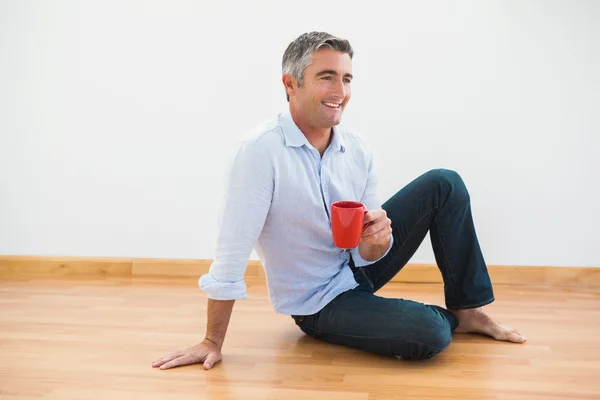 Sorrindo homem sentado com uma caneca e descalço — Fotografia de Stock