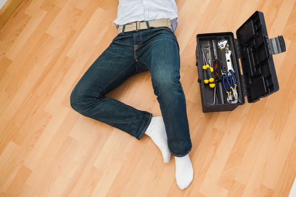 Hombre acostado con una caja de herramientas cerca de él —  Fotos de Stock