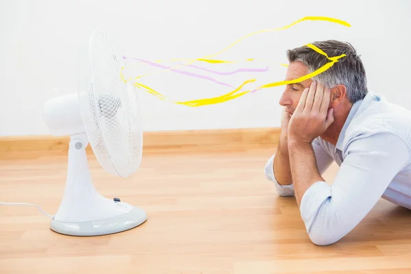 Homme allongé devant un ventilateur électronique avec des rubans — Photo