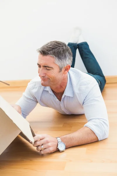 Uomo settico sdraiato sul pavimento e guardando all'interno della scatola — Foto Stock