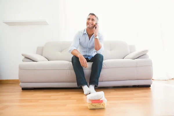 Homem sorridente a telefonar para o sofá — Fotografia de Stock