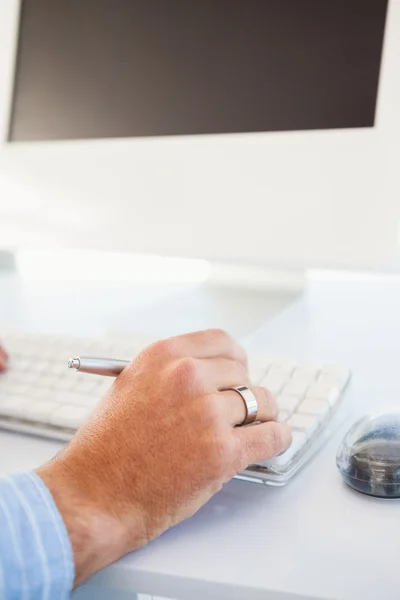 Primer plano de una mano sosteniendo el lápiz y escribiendo en el teclado —  Fotos de Stock