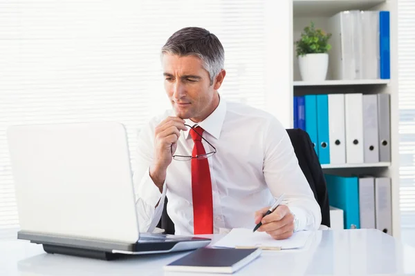 Empresario sosteniendo sus gafas y tomando notas — Foto de Stock