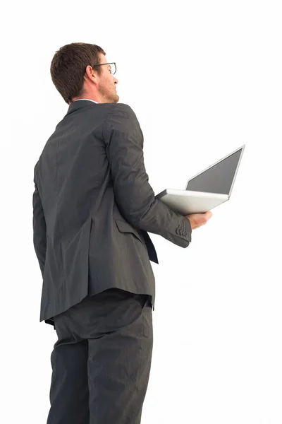 Бизнесмен смотрит вверх держа ноутбук — стоковое фото