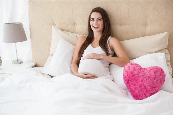 Schwangere Brünette sitzt im Bett — Stockfoto