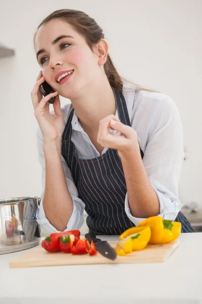 Morena bonita ao telefone enquanto cozinha — Fotografia de Stock