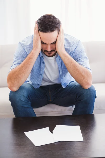 Aufgebrachter Mann sitzt Kopf in Hand auf Couch — Stockfoto