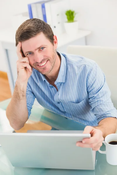 Usmívající se podnikatel pomocí jeho laptop na stole — Stock fotografie