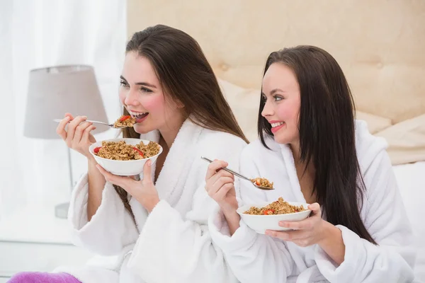 Amigos bonitos vestindo roupões de banho comendo cereais — Fotografia de Stock