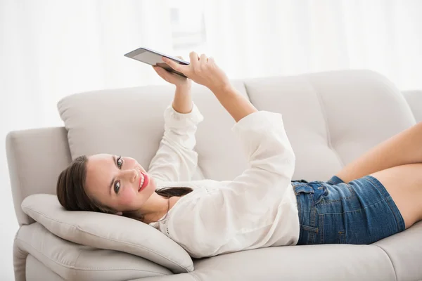 Mooie brunette met behulp van Tablet PC op de Bank — Stockfoto