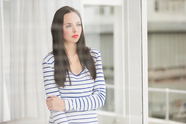 Mooie brunette kijkt uit raam — Stockfoto