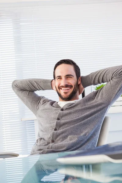 Avslappnad casual affärsman lutar sig tillbaka på hans skrivbord — Stockfoto